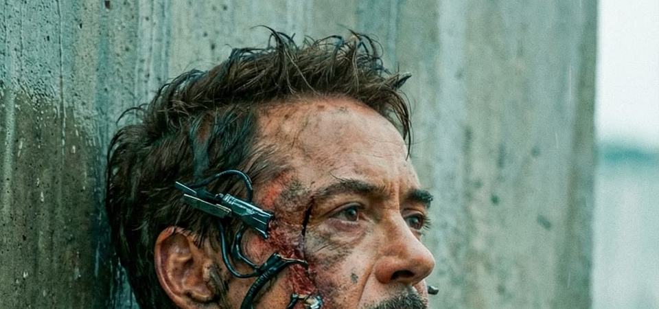 Iron Man in scorched Mark 85 armour, gauntlet raised, kneeling amid battlefield wreckage and smoke