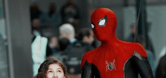 Spider-Man in his red and black suit stands beside MJ on a crowded city street